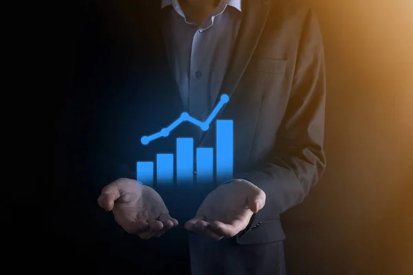 Businessman man holding a graph with positive profits growth. plan graph growth and increase of chart positive indicators in his business.more profitable and growing