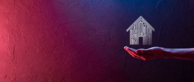 İş adamı ev ikonunu tutuyor. Marketin ev kontrollü, akıllı ev ve ev otomasyon uygulaması konsepti. PCB tasarımı ve akıllı telefonu olan kişi. Yenilik teknolojisi internet ağı kavramı