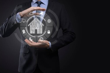 İş adamı ev ikonunu tutuyor. Marketin ev kontrollü, akıllı ev ve ev otomasyon uygulaması konsepti. PCB tasarımı ve akıllı telefonu olan kişi. Yenilik teknolojisi internet ağı kavramı