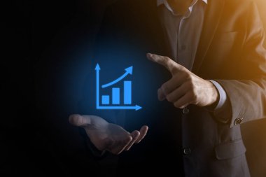 İş adamı elinde pozitif kar artışı olan bir grafik tutuyor. Grafik büyümesi ve grafik artışı işlerinde olumlu göstergeler. Daha kârlı ve büyüyen