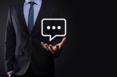 Elinde mesaj ikonu tutan bir iş adamı, elinde baloncuklu konuşma tebligat işareti var. Sohbet simgesi, SMS simgesi, yorum simgesi, konuşma baloncukları.