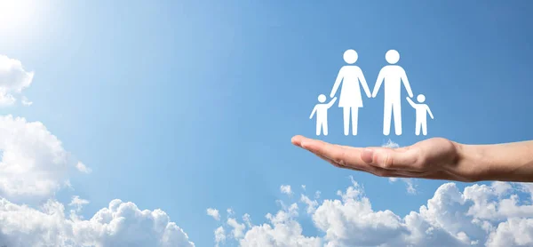 Hand on sky background holds family icon.Healthcare and life insurance concept.Father, mother, daughter and son
