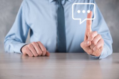 Elinde mesaj ikonu tutan bir iş adamı, elinde baloncuklu konuşma tebligat işareti var. Sohbet simgesi, SMS simgesi, yorum simgesi, konuşma baloncukları.