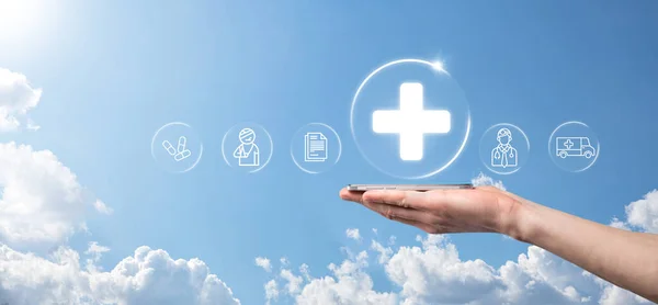 Businessman hold virtual plus medical network connection icons. Covid-19 pandemic develop people awareness and spread attention on their healthcare.Doctor,document,medicine,ambulance,patient icon