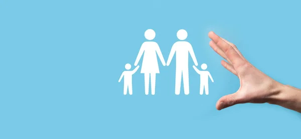 Hand hold young family icon. Family life insurance,supporting and services,family policy and supporting families concepts.Happy family concept.Copy space.mancupped hands showing paper man family.