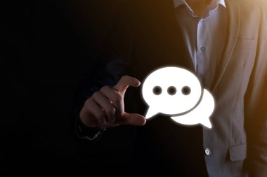 Elinde mesaj ikonu tutan bir iş adamı, elinde baloncuklu konuşma tebligat işareti var. Sohbet simgesi, SMS simgesi, yorum simgesi, konuşma baloncukları.