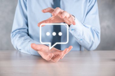 Elinde mesaj ikonu tutan bir iş adamı, elinde baloncuklu konuşma tebligat işareti var. Sohbet simgesi, SMS simgesi, yorum simgesi, konuşma baloncukları.