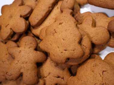 Çeşitli Şekillerde Zencefilli Kurabiyeler Bayram İkramları ve Paylaşım İçin Hazır. Bir tabak taze pişmiş zencefilli kurabiye çeşitli şekillerde, zengin kahverengi renk ve açık çatlaklar