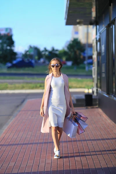 Dopo la giornata di shopping. Primo piano di una giovane donna che porta borse della spesa mentre cammina lungo la strada — Foto Stock