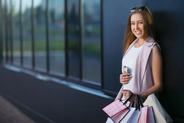 Moda alışveriş kız portre. Kız alışveriş torbaları ile telefon ile el gülümseyerek. Alışveriş kadın kavramı. — Stok fotoğraf