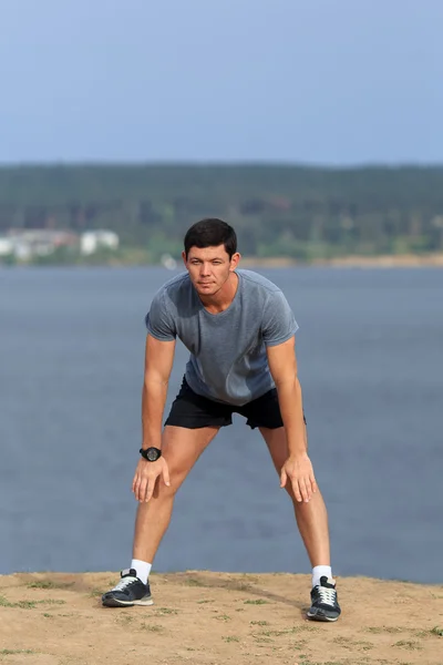 Erkek koşucu esneme egzersizi yapıyor, parkta sabah antrenmanına hazırlanıyor.. — Stok fotoğraf