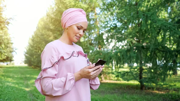 Νεαρή γυναίκα σε μωβ φόρεμα και hijab τύπους στο smartphone — Φωτογραφία Αρχείου