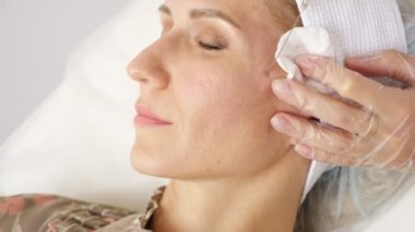 Güzellik uzmanı, bir kadının yüzünün altına uzun bir iğne yerleştirir.