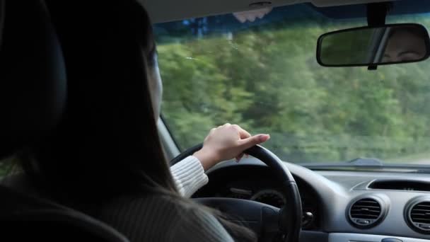 Vrouw rijdt een auto door het bos achteraanzicht — Stockvideo