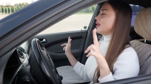 Senhora de cabelos compridos em danças brancas canta apertando as mãos no carro — Vídeo de Stock