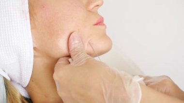 Bir kadının yüzünün altına iğne batırıp, ilaç enjekte etmeye yakın çekim.