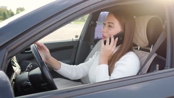 Молода жінка розмовляє по телефону під час водіння машини — стокове відео
