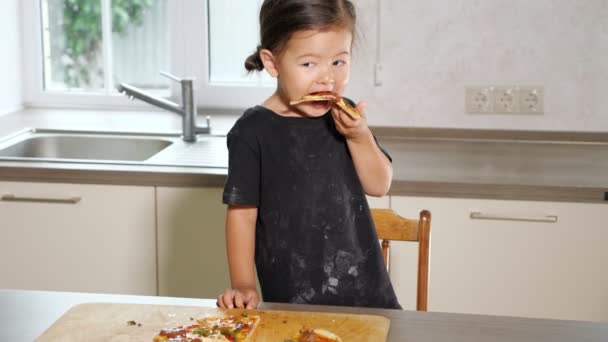 Liten flicka äter en bit nylagad pizza — Stockvideo