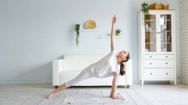 Hamile kadın utthita parsvakonasana 'yı evde yapıyor.