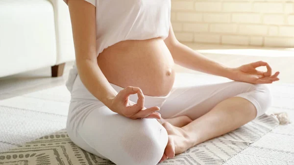 Pregnant lady with bare tummy meditates on floor at home — Stock Photo, Image