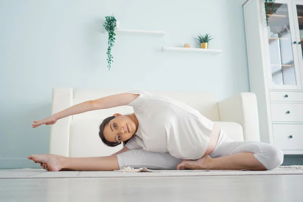 Beautiful pregnant woman exercising while sitting in lotus position — Stock Photo, Image