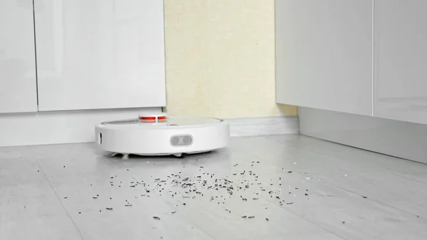 Robot vacuum cleaner with brushes removes garbage from floor — Stock Photo, Image