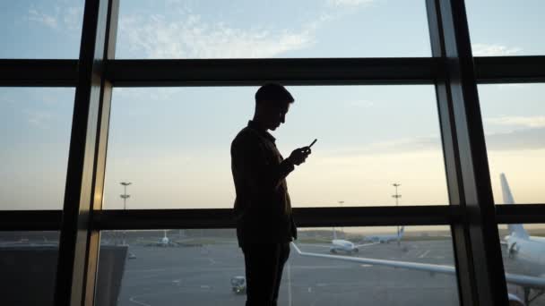 공항 창문 근처에서 스마트폰으로 인터넷 검색하는 사람 — 비디오