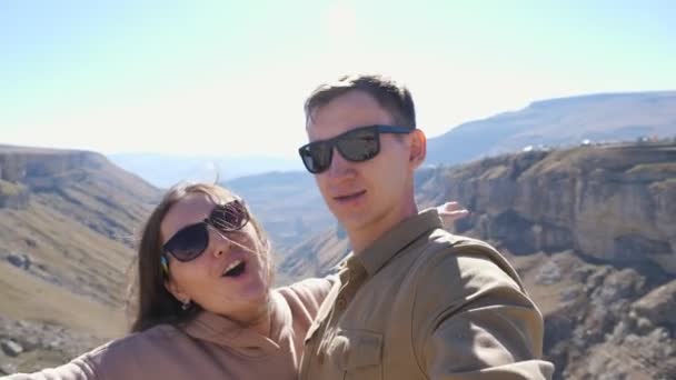 Szczęśliwa para w okularach przeciwsłonecznych robi selfie przeciwko górom — Wideo stockowe