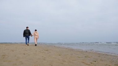 Çift boş Hazar sahili boyunca el ele yürür.