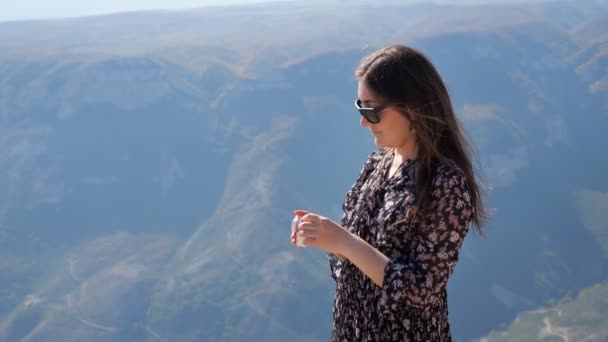 Жінка одягає навушники, дивлячись на стародавні гори — стокове відео