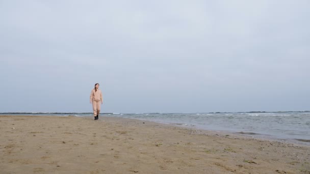 Mujer bonita en chándal rosa camina a lo largo de la playa del mar Caspio — Vídeo de stock