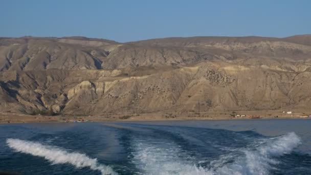 Segelmotorboot-Spur auf ruhigem See gegen Berge — Stockvideo