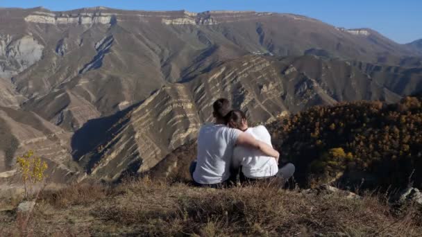Man en vrouw knuffelen op heuvel met droog gras tegen bergen — Stockvideo