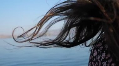 Mavi su arka planında dalgalı esmer saçların yakın çekimi