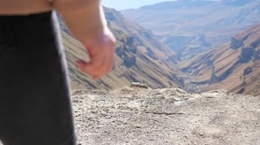 Tanınmayan genç bir kadın uçurumun kenarına yürür.