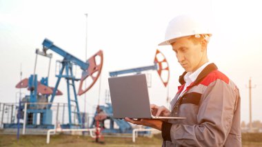 Petrol pompasının arka planında dizüstü bilgisayarı olan petrol endüstrisi mühendisi.