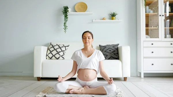 Tranquil pregnant woman meditates in lotus pose at home — Stock Photo, Image