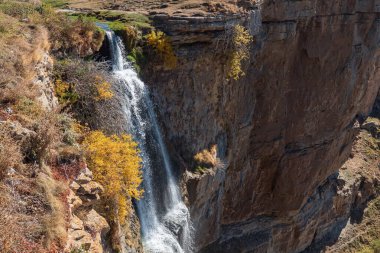Mavi gökyüzünün altındaki vadideki sarp kayalıklarda inanılmaz şelale