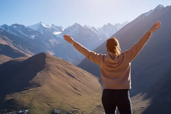 Brunette femme étend ses bras sur les côtés sur le fond de montagnes enneigées — Photo
