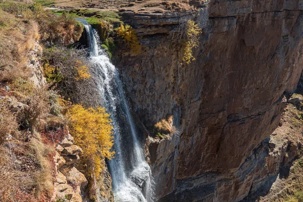 Mavi gökyüzünün altındaki vadideki sarp kayalıklarda inanılmaz şelale