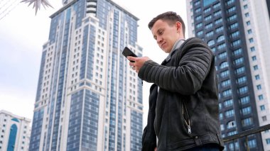 Ceketli, konsantre olmuş yakışıklı adam akıllı telefona bakar.