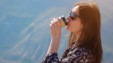 Güzel kadın kahve içiyor ve manzaranın tadını çıkarıyor.