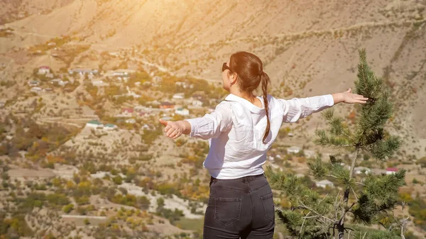 Mladá žena v bílé košili těší pohled na údolí s roztaženýma rukama, zadní pohled — Stock fotografie