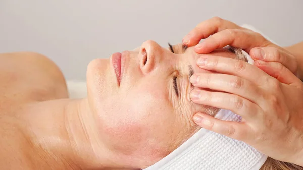 Skilled masseur runs fingers on beauty salon client forehead — Stock Photo, Image