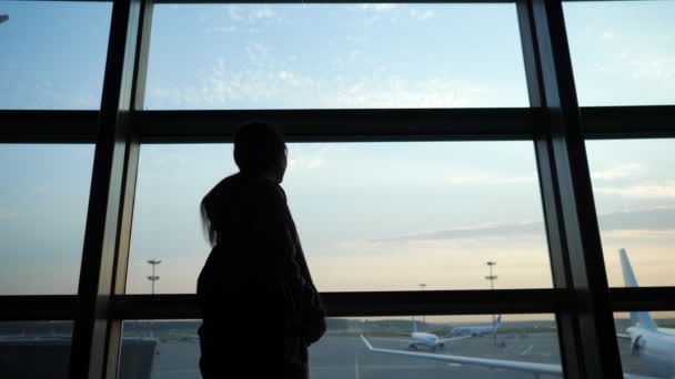 Silhouette de femme avec grand sac se promène le long du terminal — Video