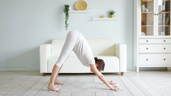 Pregnant woman does adho mukha svanasana on floor at home — Stock Photo, Image