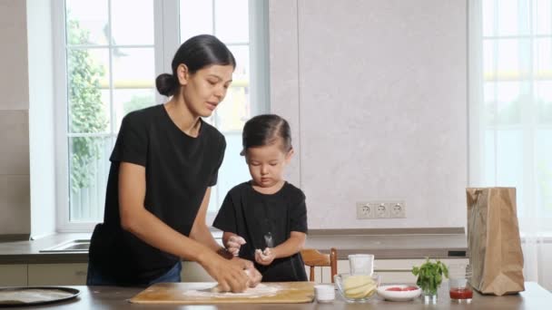 Mère et petite fille agitent et étirent la pâte élastique — Video