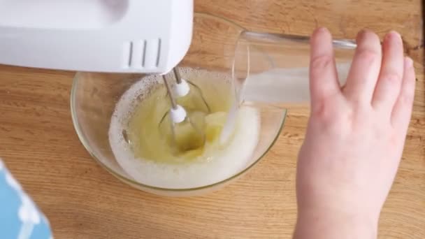 Kvinna slår äggvita med socker med hjälp av en elektrisk mixer — Stockvideo