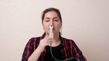 Genç bir kadın burun deliklerini nebulizörle soluyor.