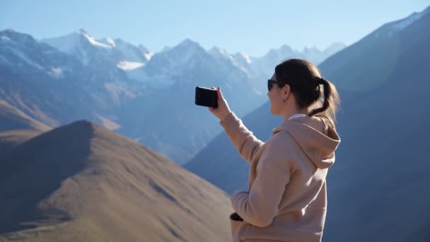 3.年轻女子在手机上为美丽的高山美景拍照，她的山顶上覆盖着白雪 — 图库视频影像